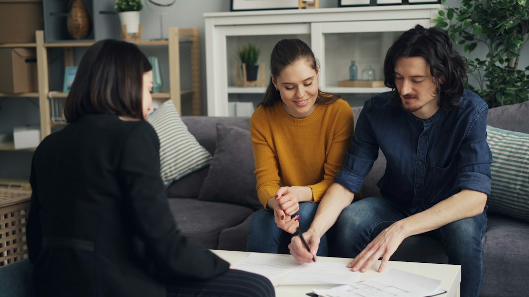 Ein Paar bespricht Immobilienunterlagen mit einer Beraterin – Symbolfoto